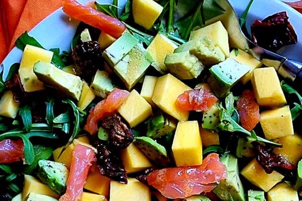 Une assiette d'une salade sucrée salée au saumon fumé, avocat et mangue