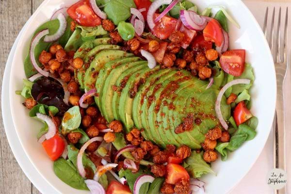 Une assiette blanche de salade vegan aux pois chiches et avocat