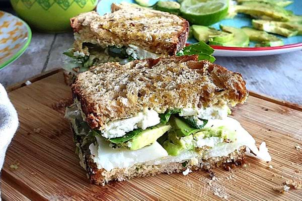 Deux sandwichs frais à l'avocat et la feta sur une planche à découper en bois