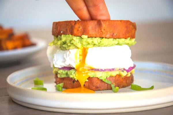 Une personne mettant deux doigts sur un brunch burger dans une assiette