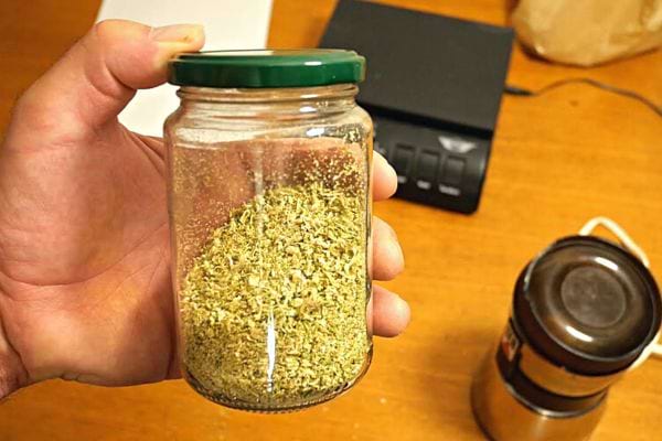 Une personne tenant du sel de céleri dans un bocal en verre avec un couvercle vert 