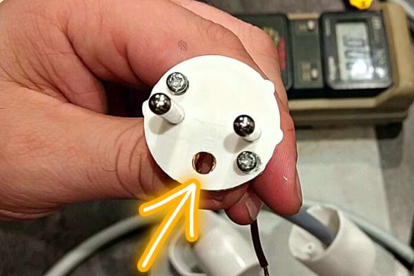 Une personne tenant une fiche électrique avec un trou à l'intérieur 