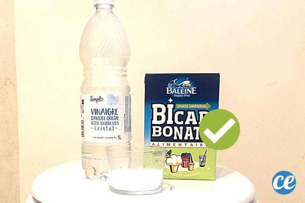 Une bouteille de vinaigre blanc et un carton de bicarbonate de soude sur une cuvette de toilette