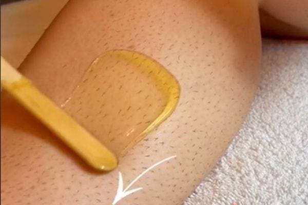 une personne applique de la cire orientale sur le mollet
