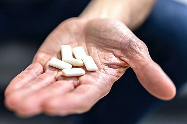 Une personne ayant plusieurs petit chewing-gum à l'intérieur de sa main