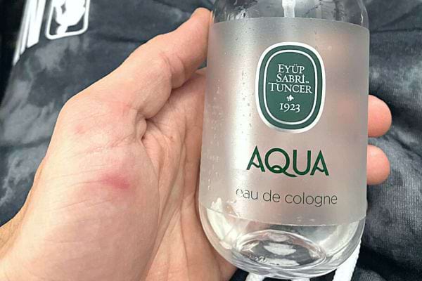 Une personne tenant une bouteille d'eau de Cologne