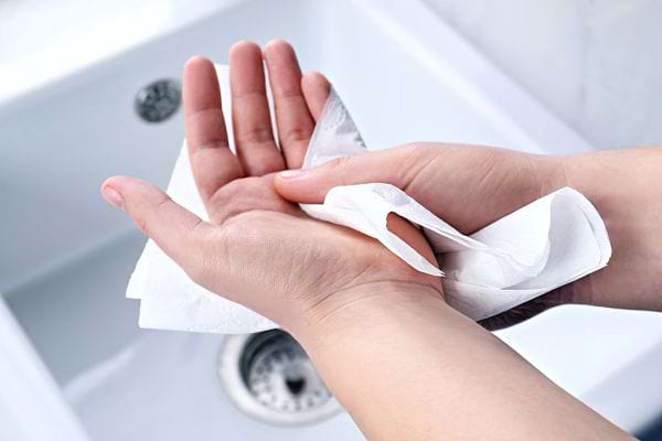 A person wiping their hands with a tissue 