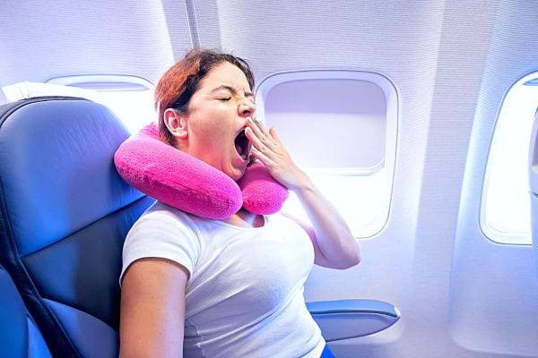Une femme ayant un coussin violet autour du cou en train de bâiller