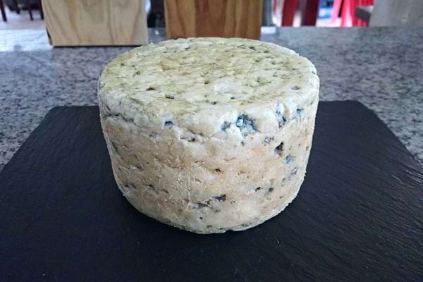 Un gros fromage rond sur un plateau noir