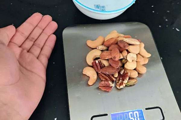 Une personne ayant mit plusieurs fruits secs sur une petite balance 