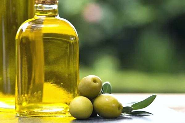 Une bouteille en verre d'huile d'olive avec trois olives 