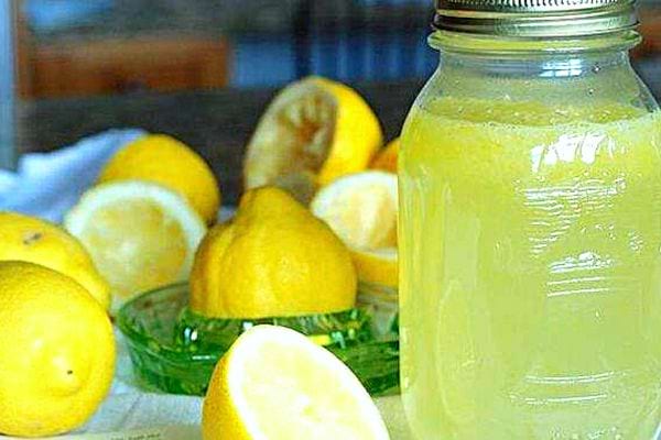 Du jus de citron dans verre avec un couvercle avec plusieurs citrons découpés