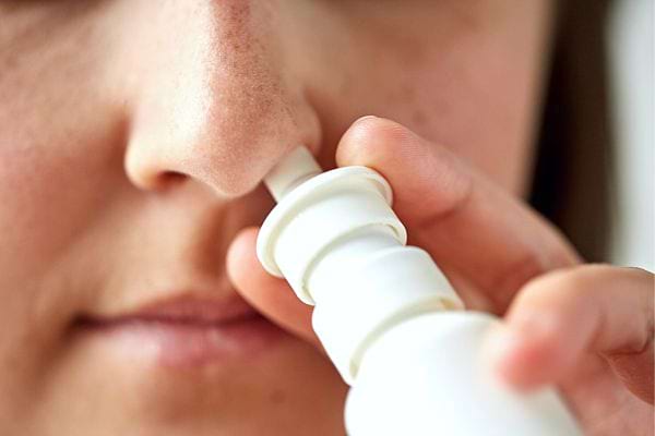 Une femme utilisant un décongestionnant nasal