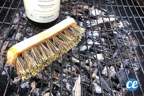 une grille de barbecue avec une brosse et du savon noir liquide à l'huile d'olive