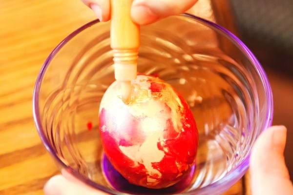 un enfant peint un oeuf dans un petit bol