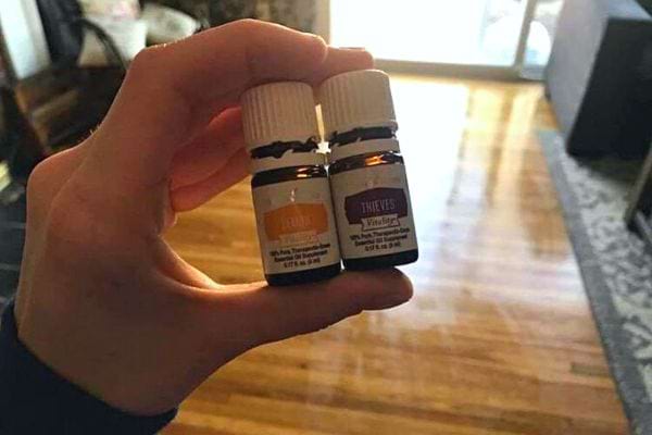 Une personne tenant dans sa main deux petites huiles essentielles 