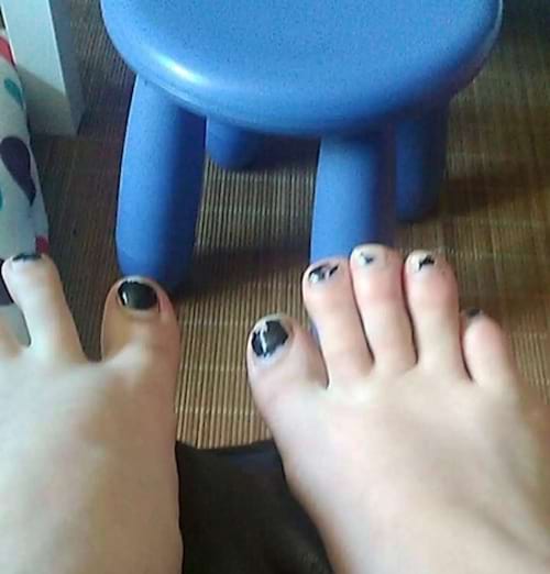 Des pieds blancs avec du vernis noirs écaillés sur les ongles