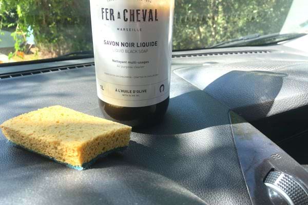 une bouteille de savon noir Fer à Cheval posé sur le tableau de bord d'une voiture