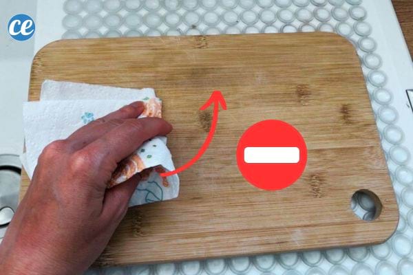 Une personne tenant un sopalin dans sa main sur une planche à découper en bois