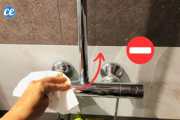 Une personne tenant un sopalin dans sa main sur une surface de douche