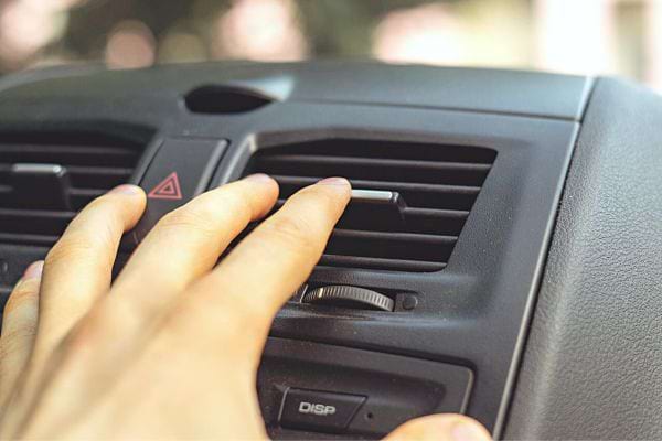 Une personne touchant la ventilation de climatisation dans sa voiture 