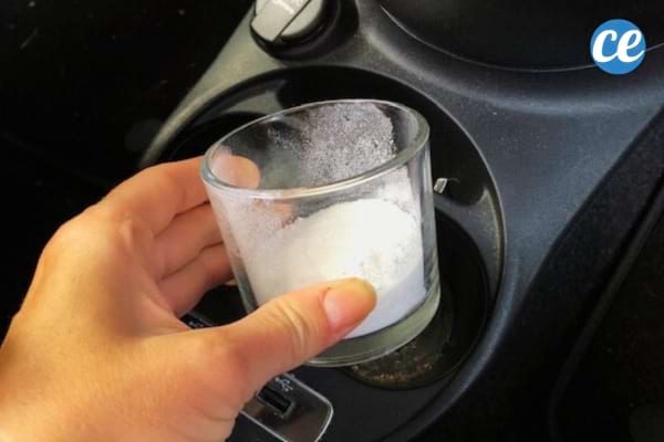 main qui dépose un récipient de bicarbonate de soude dans la voiture