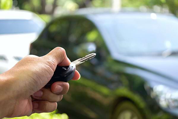 Une personne appuyant sur un bouton de la clé de sa voiture qui est à distance 