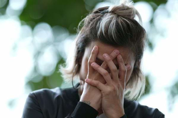 Une femme blanche ayant le visage dans ses mains avec un air "dépité"