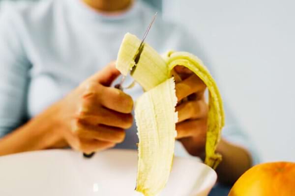 Une femme qui mange de la banane riche en potassium et magnésium pour lutter contre les pieds gonflés