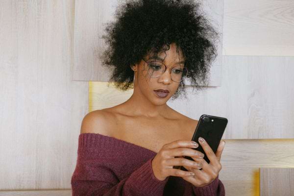 Une femme noire ayant un smartphone dans ses mains