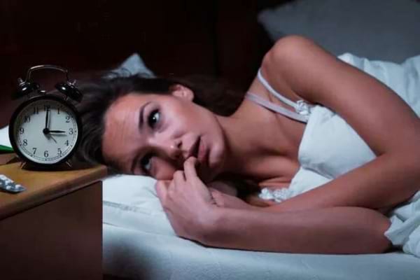 Une femme qui regarde son réveil pendant la nuit à cause de trouble respiratoire