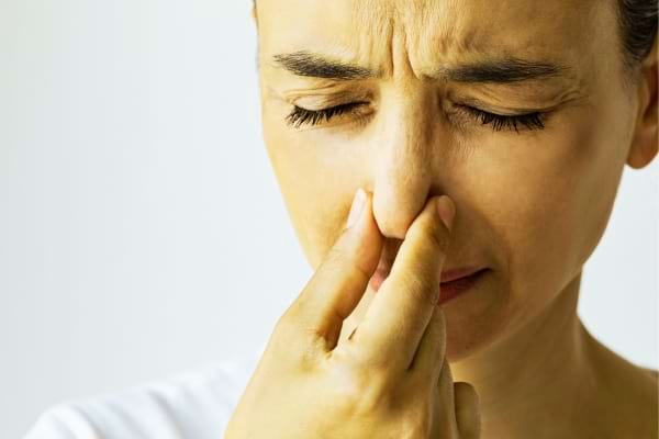 Une femme qui se pince le nez à cause de flatulences excessives