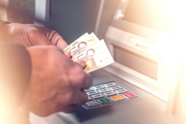 une personne retire des billets de 50€ à un distributeur automatique