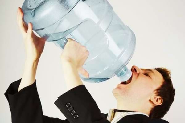 Un homme qui boit beaucoup d'eau pour lutter contre les pieds gonflés