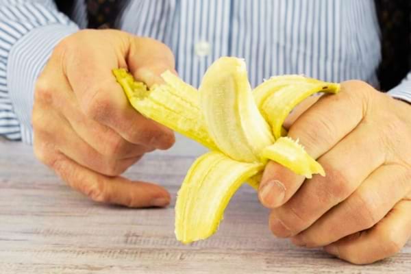 Un homme qui épluche une banane pour la manger et déloger une arête de poisson