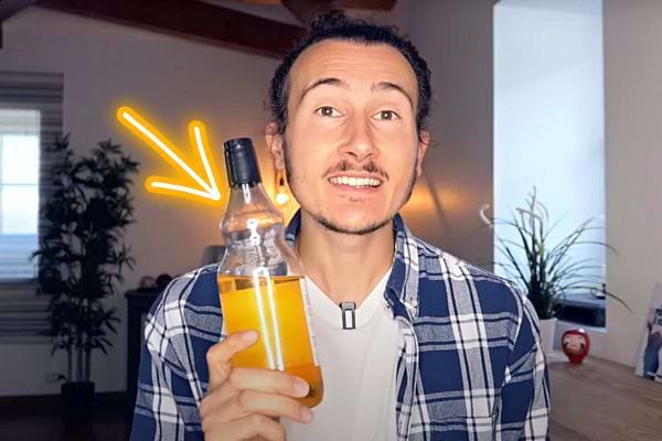 Un homme tenant une bouteille en verre de vinaigre de cidre