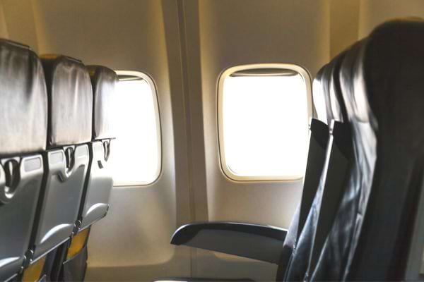 une rangée de sièges vides dans un avion avec des hublots ouverts
