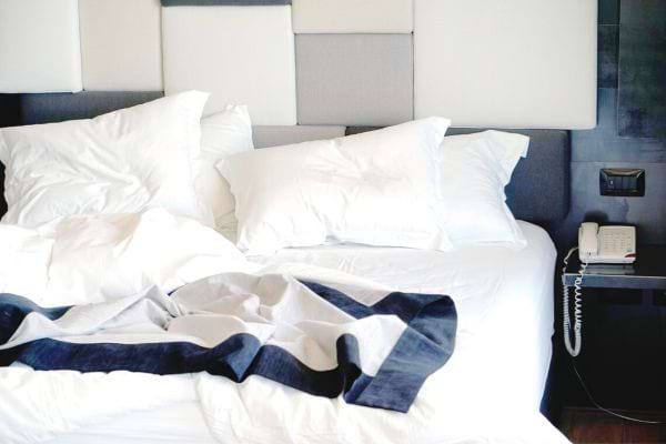 Un lit de chambre d'hôtel dépareillée avec du linge blanc