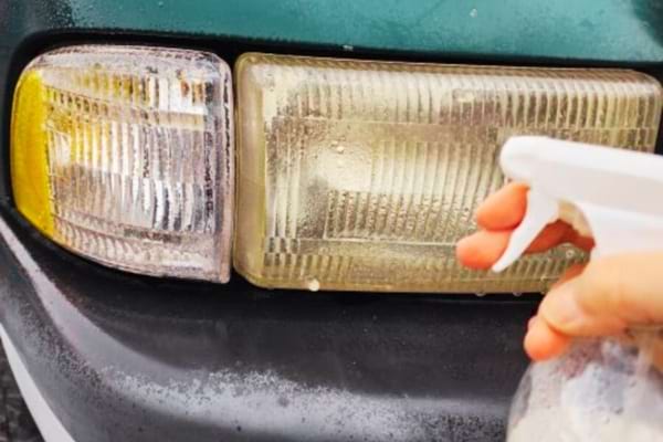 De l'alcool ménager pulvérisé sur des phares de voiture pour les nettoyer