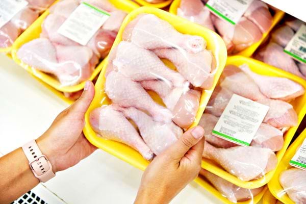 Une personne tenant un paquet contenant plusieurs cuisses de poulet 