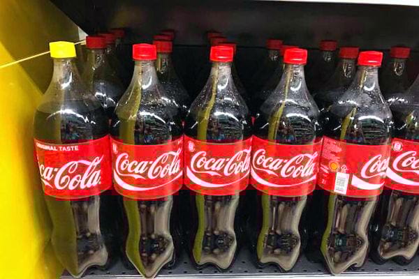 Plusieurs bouteilles de Coca-Cola avec une bouteille qui a un bouchon jaune