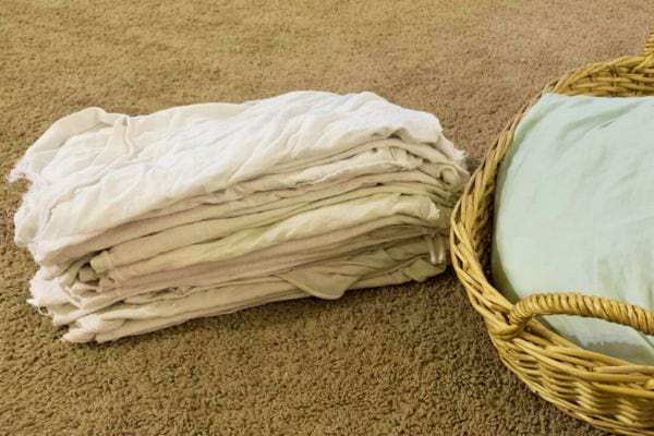 Plusieurs torchons blancs sur le sol avec un panier à linge 