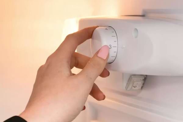 Quelqu'un qui règle un thermostat de frigo pour le mettre à bonne température