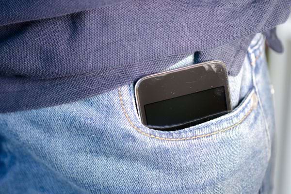 Un téléphone noir dans une poche de jeans bleu