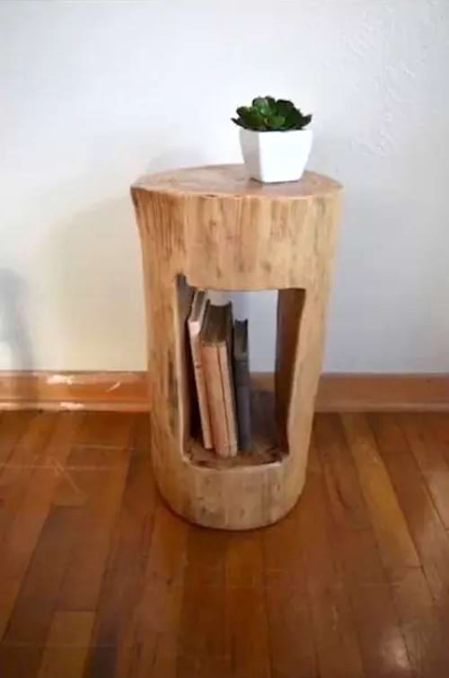 Un tronc d'arbre transformé en table de rangement pour des livres et une petite plante 
