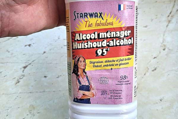 Eine Person hält eine weiße Flasche Haushaltsalkohol in der Hand