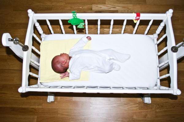 Un bébé noir habillé d'un pyjama blanc qui dort dans un berceau