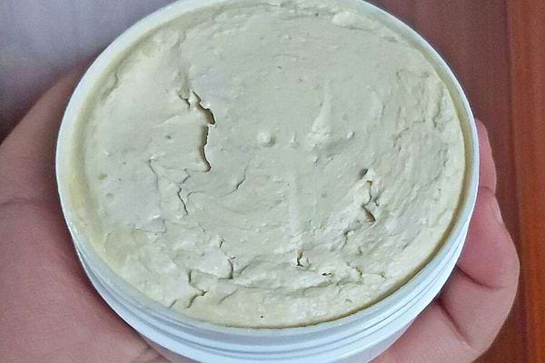 Eine Person hält einen Topf Butter