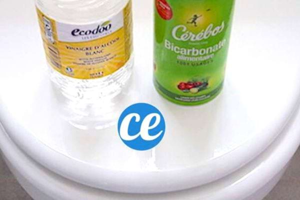 Une bouteille de vinaigre blanc et du bicarbonate vert sur une toilette blanche