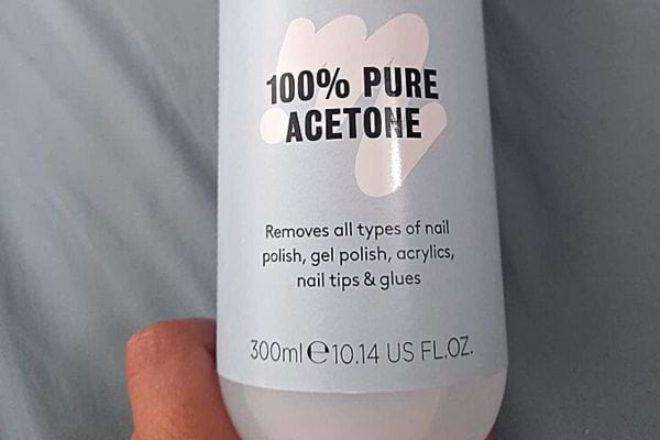 Eine Person hält eine Flasche Nagellackentferner in der Hand
